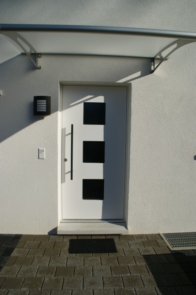 Weisse, klassische Eingangstüre mit drei Fenstern und Stange als Türknauf. Die Firma Weidmann AG in Möhlin baut Ihre Wunschtüre exakt ein.