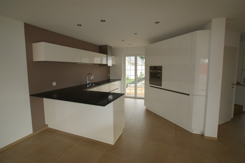 Weiss- glänzende Küche in modernem Design mit schwarzer Marmorplatte als Arbeitsfläche. Die Firma Weidmann AG in Möhlin baut Ihre Küche nach ihrem Geschmack.