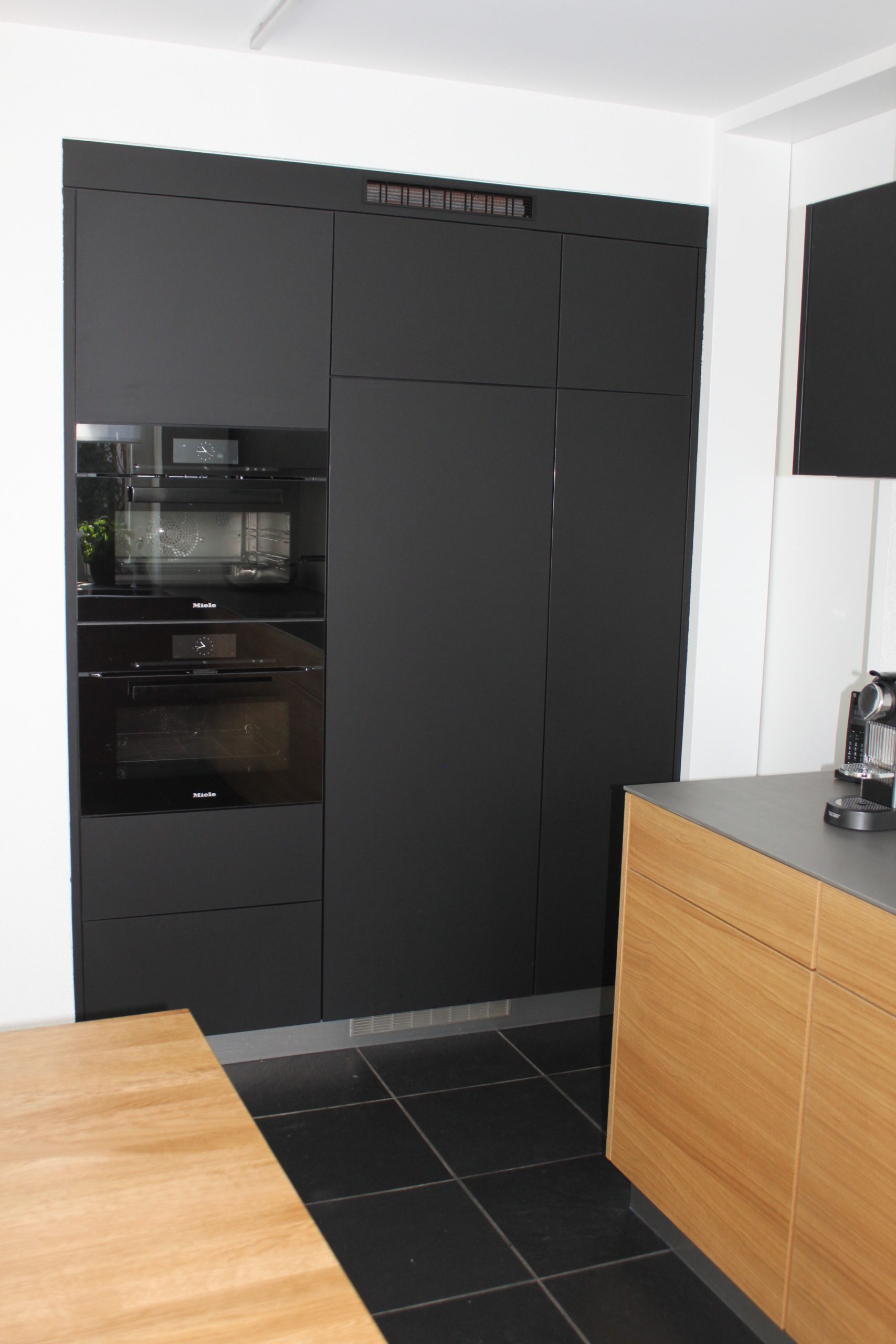 Elegenate schwarze Schrankwand mit integriertem Backofen. Die Firma Weidmann AG in Möhlin baut Ihre Traumküche.