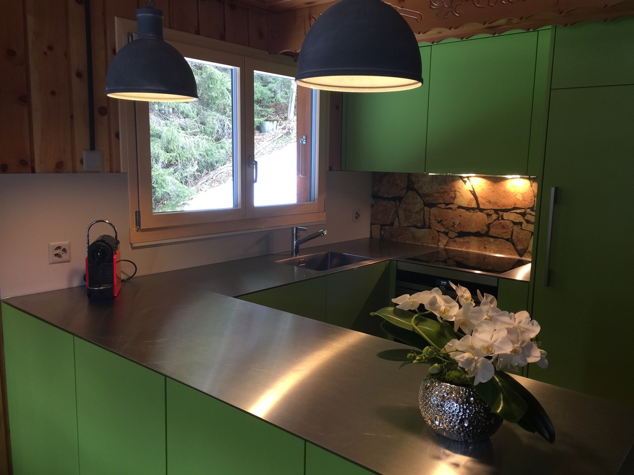 Grüne, massive Glanzküche und schöner Kücheninsel in weiss mit schwarzer Steinabdeckung. Die Firma Weidmann AG in Möhlin baut Ihre Traumküche.