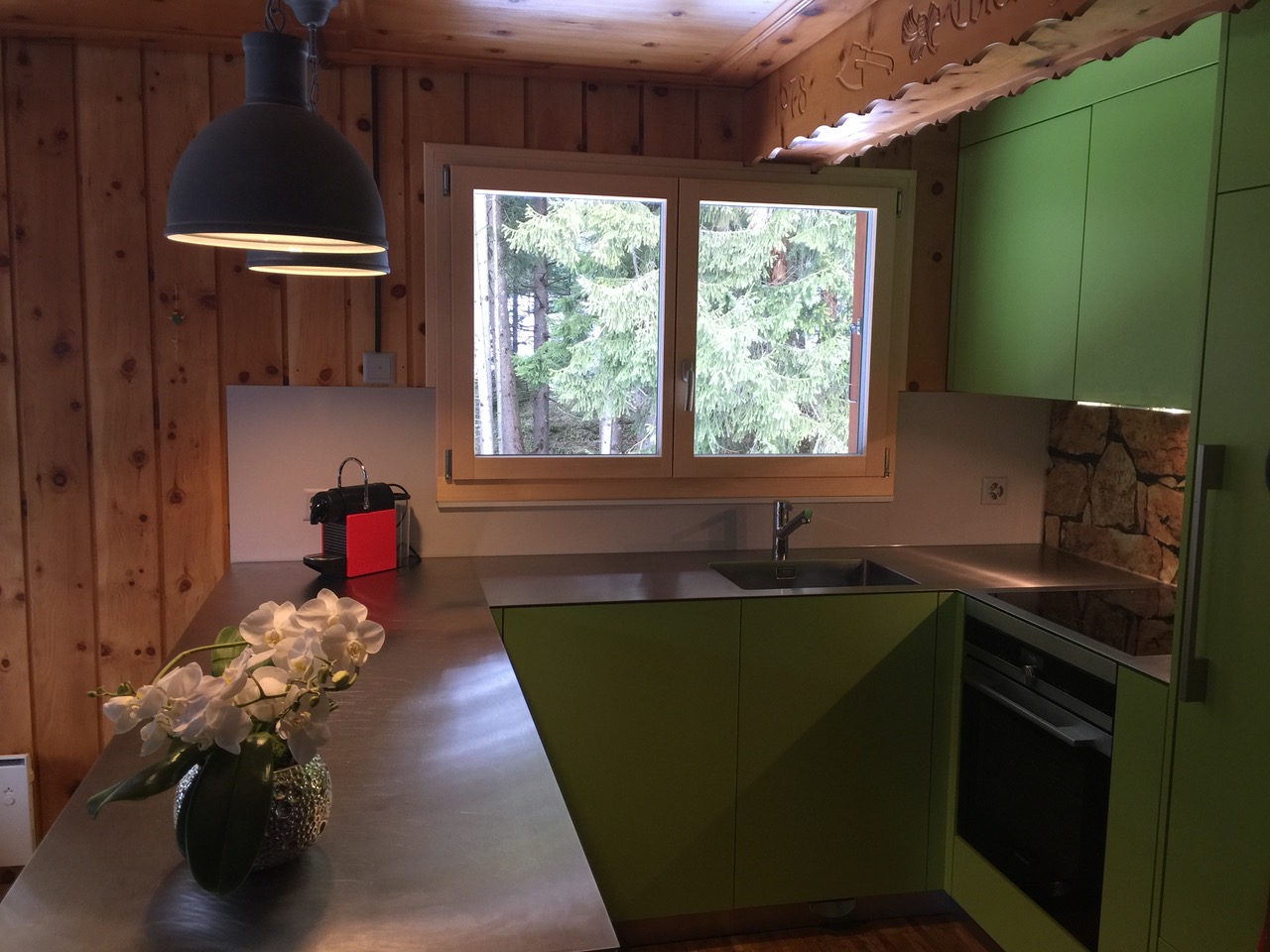 Grüne, massive Glanzküche und schöner Kücheninsel in weiss mit schwarzer Steinabdeckung. Die Firma Weidmann AG in Möhlin baut Ihre Traumküche.