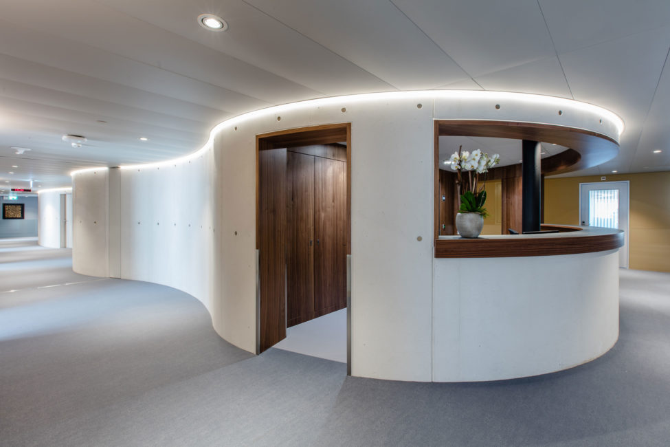 Die Rezeption des Merian Iselin Krankenhauses in Basel mit schönen dunklen Holzschränken im Hintergrund und eine passende Holzverkleidung des Empfangs. Schöner Innenausbau von der Firma Weidmann AG in Möhlin.