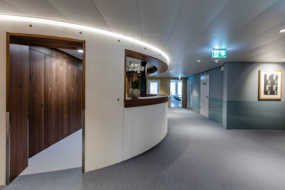 Die Rezeption des Merian Iselin Krankenhauses in Basel mit schönen dunklen Holzschränken im Hintergrund und einer passender Holzverkleidung des Empfangs. Innenausbau der Firma Weidmann AG in Möhlin.